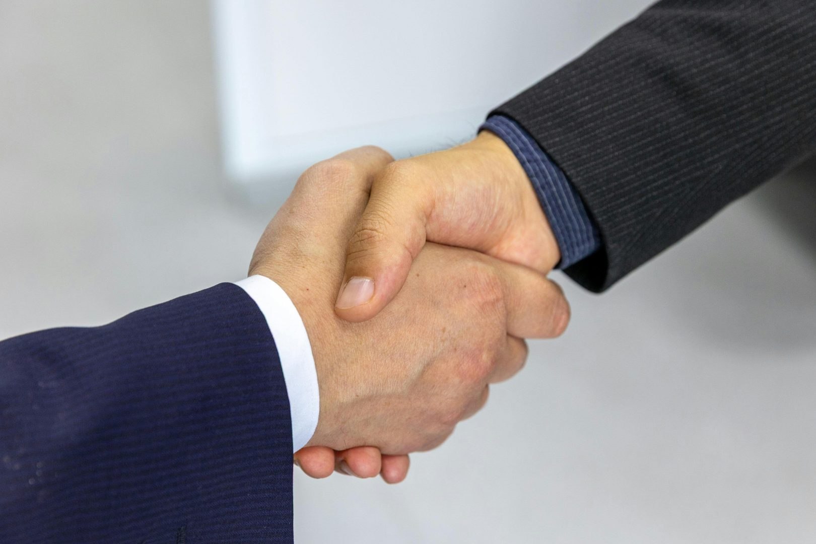Two businessmen shaking hands on a digital business sale agreement